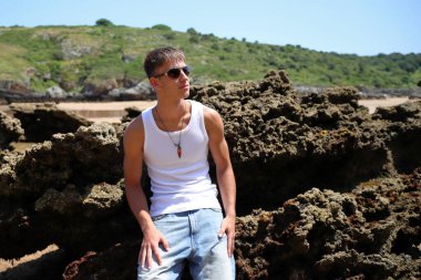 Plajda güneş gözlüklü genç, sıradan bir genç, yaz yaşam tarzı.