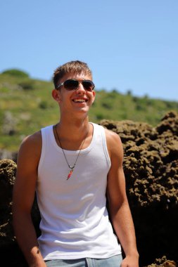 Plajda güneş gözlüklü genç, sıradan bir genç, yaz yaşam tarzı.