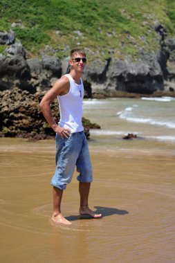 Plajda güneş gözlüklü genç, sıradan bir genç, yaz yaşam tarzı.