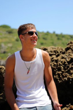 Plajda güneş gözlüklü genç, sıradan bir genç, yaz yaşam tarzı.