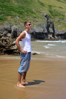 Plajda güneş gözlüklü genç, sıradan bir genç, yaz yaşam tarzı.