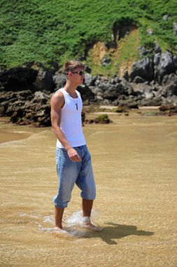 Plajda güneş gözlüklü genç, sıradan bir genç, yaz yaşam tarzı.