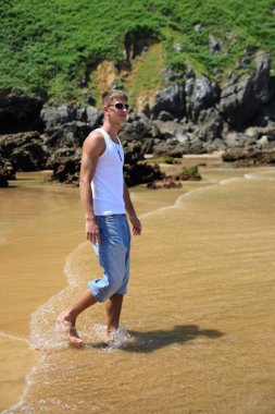 Plajda güneş gözlüklü genç, sıradan bir genç, yaz yaşam tarzı.