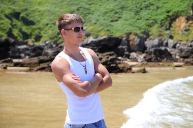 Plajda güneş gözlüklü genç, sıradan bir genç, yaz yaşam tarzı.