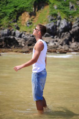 Plajda güneş gözlüklü genç, sıradan bir genç, yaz yaşam tarzı.