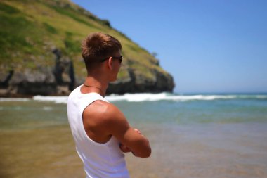 Plajda güneş gözlüklü genç, sıradan bir genç, yaz yaşam tarzı.