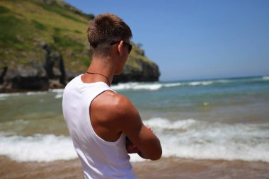 Plajda güneş gözlüklü genç, sıradan bir genç, yaz yaşam tarzı.