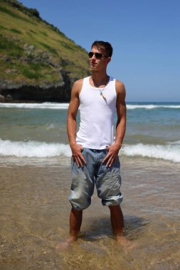 Plajda güneş gözlüklü genç, sıradan bir genç, yaz yaşam tarzı.