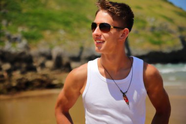 Plajda güneş gözlüklü genç, sıradan bir genç, yaz yaşam tarzı.