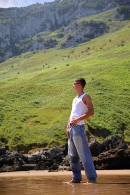 Beyaz kolsuz tişörtlü, güneş gözlüklü, yaz plajında bronz tenli, sıradan bir genç kız.