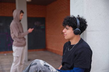 Dışarıda akıllı telefonlardan, çeşitlilikten ve iletişim sorunu kavramından rahatsız olan iki genç çocuk var.