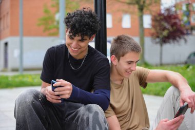 Dışarıda akıllı telefonları olan iki genç arkadaş ekrana bakıyor, teknoloji iletişimi.