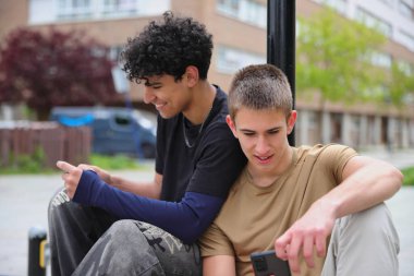 Dışarıda akıllı telefonları olan iki genç arkadaş ekrana bakıyor, teknoloji iletişimi.