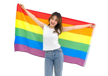 Young asian female LGBTQ stand  smiling, holding big rainbow gay pride unity flag showing same sex love equality. Portrait on white background with studio light. LGBTQ Lifestyle Pride Month