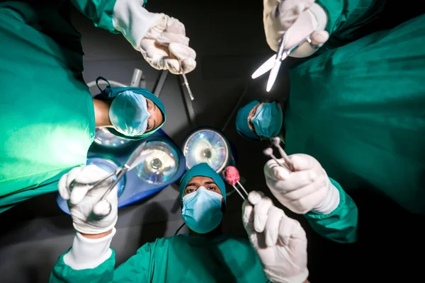 一组穿着外科绿色长袍的外科医生和护士在手术室进行外科手术 底部的观点 紧急外科护理概念 — 图库照片