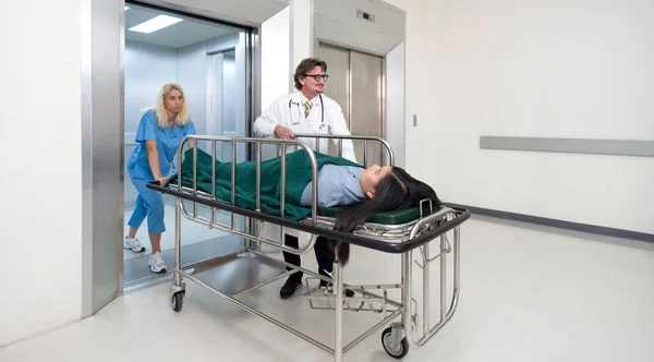 救护人员和护士把病人的床从电梯里推到医院的急救室 — 图库照片
