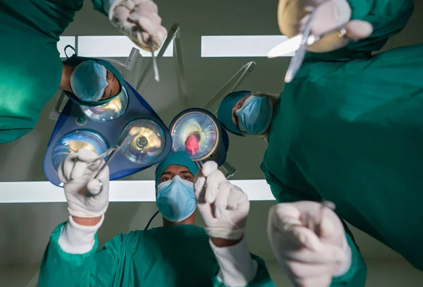 紧急外科护理的概念 一组穿着外科绿色长袍的外科医生和护士在手术室进行外科手术 底部视图 — 图库照片