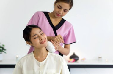 Genç ve güzel bir kadın Thai bitkisel masaj yaptırıyor. Boyun gerdirmeye yakın. Sakin atmosfer. Huzurlu kaplıca tedavisi kavramı.