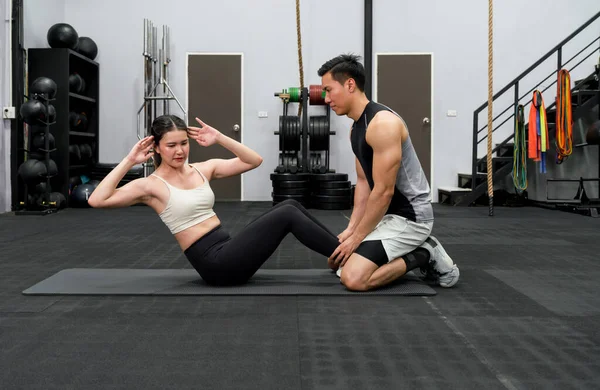 Fit couple exercising together in a well-equipped gym, engaged in a dynamic strength training workout. An image reflecting teamwork, motivation, and a healthy lifestyle.
