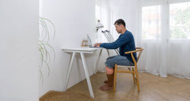 Kırık bacağı olan bir adam işine dalmış, bir ofiste ya da evde çalışan bir iş yerinde oturuyor. Dizüstü bilgisayarında çeşitli görevlere dalmış, verimlilik ve odaklanma hissini aktarıyor..