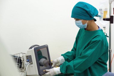Steril ameliyat elbisesi içinde kendini adamış bir sağlık uzmanı yüksek teknolojili bir makine, son tıbbi gelişmeler, teknoloji ve tıbbın kesişiminin altını çiziyor..