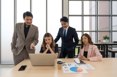 Çağdaş bir ofis ortamında dizüstü bilgisayardaki verileri incelerken coşkuyla iş birliği yapan iş adamları.