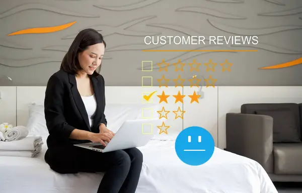 Focused businesswoman perusing through customer reviews on her laptop while sitting comfortably on a bed in a calm and serene environment. Customer review satisfaction feedback survey concept.