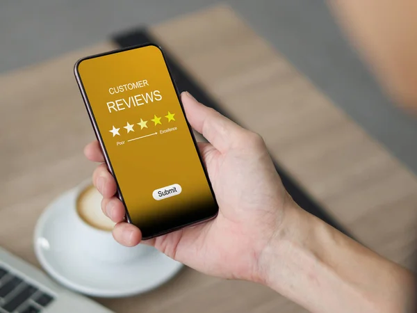 Yakından bir akıllı telefon tutuyordu. Telefonun ekranında beş yıldız görünüyor..