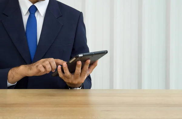 Digital Life Exploration. A focused businessman in dark blue suit typing on tablet computer.