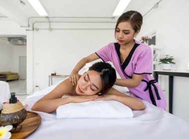 Profesyonel bir masöz yumuşak havlulara sarılı rahat bir kadına terapi masajı yapar. Huzurlu bir kaplıcadaki atmosfer.