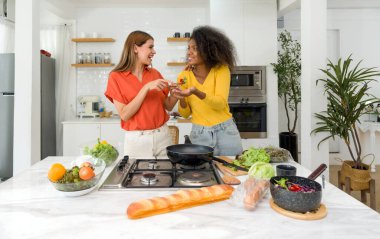 İyi aydınlatılmış bir mutfakta, anlamlı bağlantıların ve arkadaşlığın güzelliğini kutlarken, iki kadın arasındaki iç açıcı bağlantıyı keşfedin..