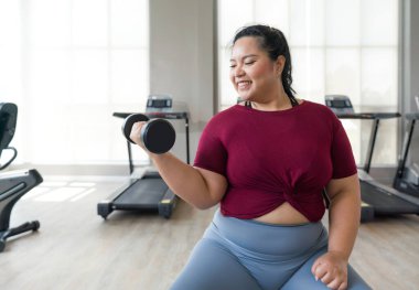 Asyalı kadın spor salonunda ağırlık kaldırıyor, güçleniyor ve sağlıklı oluyor..