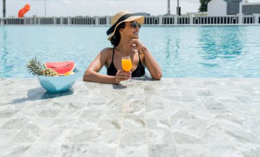 Havuz kenarında bikinili bir kadın güneşli bir günde güneşleniyor ve dinleniyor..