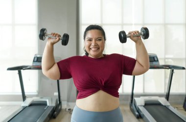 Asyalı büyük beden kadın spor salonunda ağırlık kaldırıyor, güçleniyor ve sağlıklı oluyor..