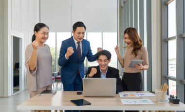 Başarılı iş adamları bir masanın etrafında toplanır ve gülümseyerek yumruklarını kaldırırlar. Liderlik kavramı.