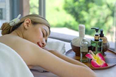 Holistik lüks sağlık deneyimi. Huzuru teşvik eden elementlerle çevrili, rahatlatıcı bir spa ortamının içinde sakin bir şekilde uzanan sakin bir kadın..