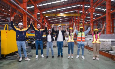 Group of worker in safety attire, including hardhat and high-visibility vest, is holding hands up high in a celebratory or team-building gesture. They are smiling and looking directly at the camera.