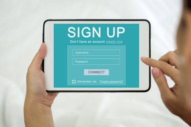 Kimliğini online olarak oluşturmaya odaklanmış bir kadın tablet bilgisayardaki bir hesaba kaydoluyor. Dijital Yaşam Keşfi.