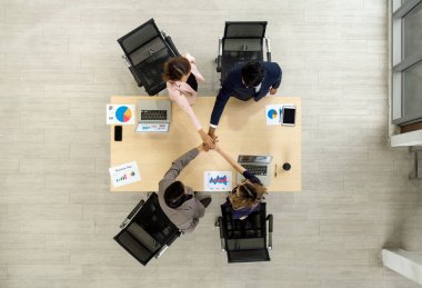 İş ortağı modern ofiste el ele tutuşuyor. İş adamları iş planıyla modern ofiste buluşacak. Laptop, tablet, cep telefonu ve dokümanlarla birlikte. Üst görünüm