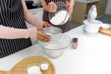 Mutfakta fırın malzemesi, renkli krema ve elektrikli mikser ile el eleme unu..