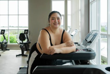 Büyük beden bir kadın spor salonunda duruyor, dinleniyor ya da egzersiz yapmaya hazırlanıyor..