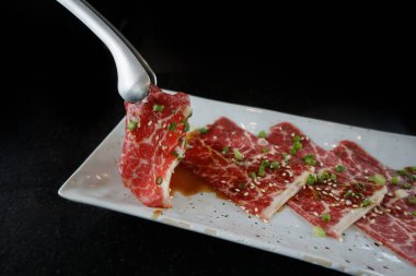 Wagyu Avustralya, çok yüksek mermerli lezzetli bir et, beyaz tabakta servis ediliyor, soslu ve soğanlı..