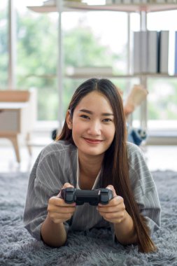 Genç Asyalı kadın konsol oyunu oynuyor. Oturma odasında rahatlayın, hafta sonunun keyfini çıkarın. Stressiz konsept.
