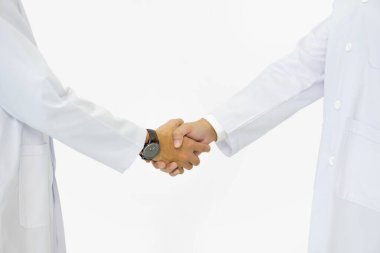 Beyaz önlüklü bir bilim adamı ve sağlık görevlisi beyaz arka planda el sıkışıyor. Yakın çekim.