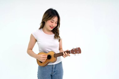 Young asian woman in white t-shirt and jean playing an Ukulele guitar. Portrait on white background with studio light.