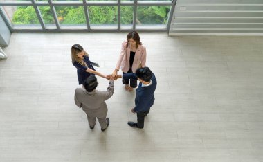 İş ortağı modern ofiste el ele tutuşuyor. Güneş üzerlerine doğarken pencerenin yanında dikiliyorlar..