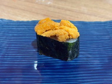 Uni Gunkan Maki. Atlantik deniz kestanesi eti Gunkan Sushi mavi seramik tabakta servis edilir.