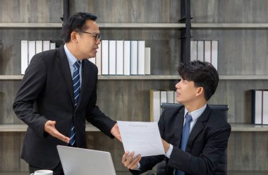 Modern bir ofiste iki profesyonel erkek bir tartışmaya girer. Bir adam tutkuyla konuşuyor, diğeri ise elinde bir kontrat belgesi tutarken dikkatle dinliyor..