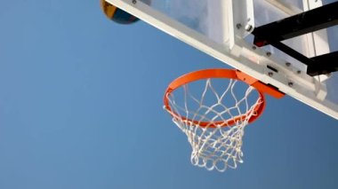 Bir basketbol topu potaya çarptı ve parlak mavi gökyüzüne doğru uçtu.