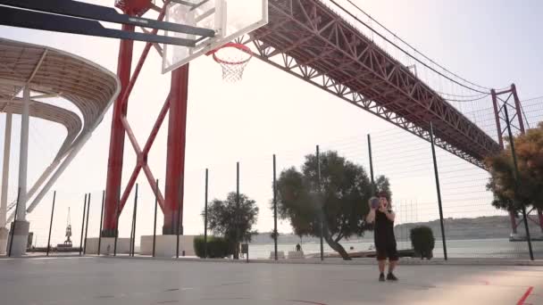 Man Throws Basketball Hoop Sunny Day Bridge River Background Walks — Stock Video